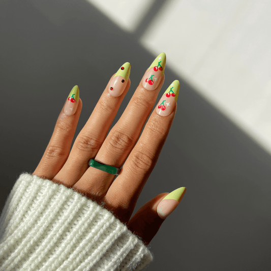 Stylish cherry-themed press-on nails in sunlight