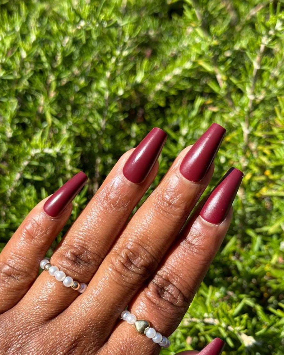 Burgundy press-on nails in a natural setting