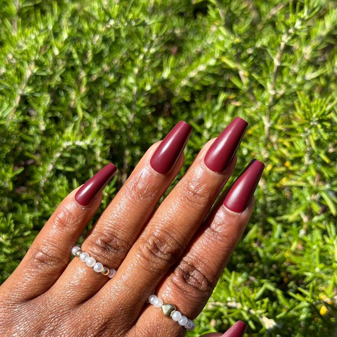 Burgundy press-on nails in a natural setting