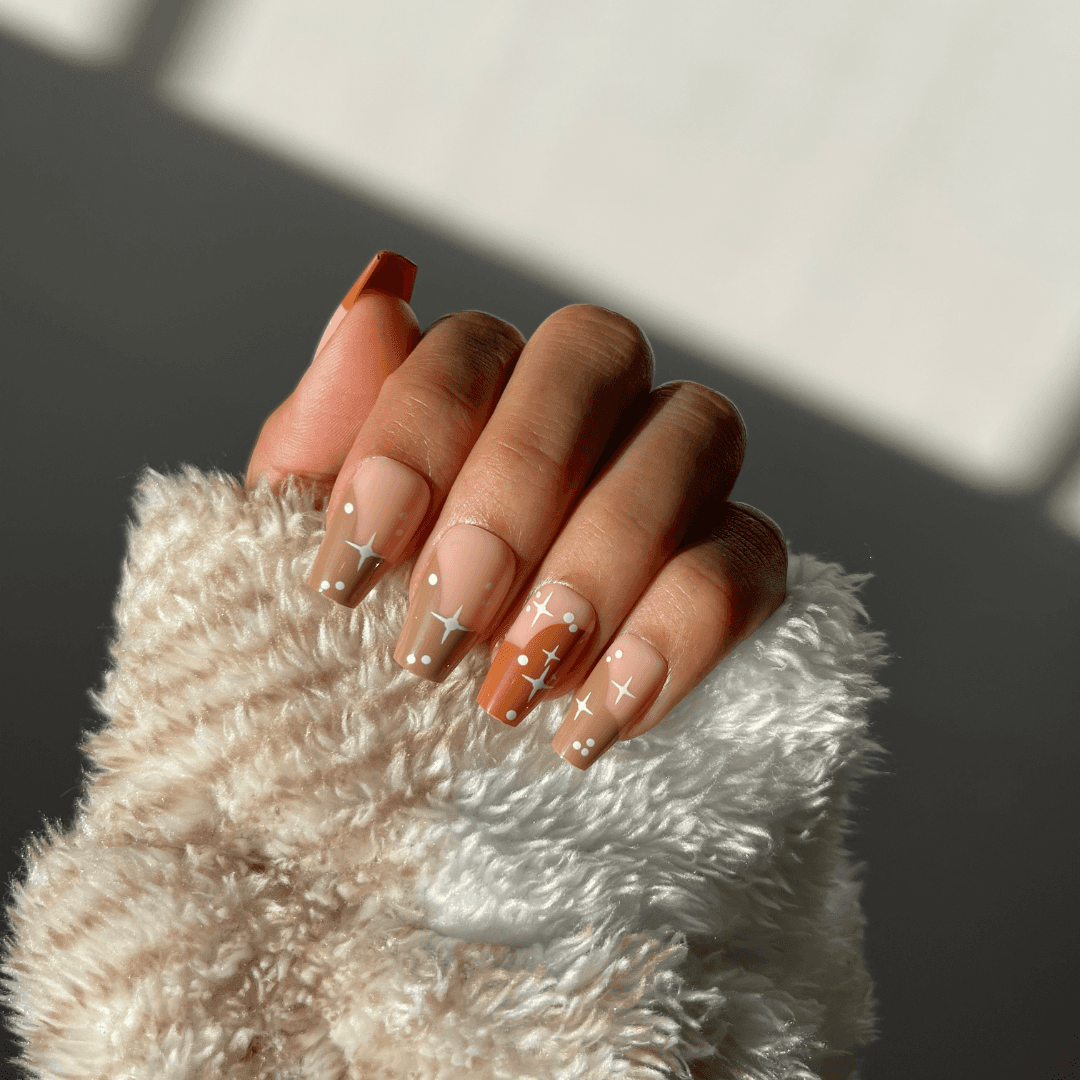 Hazel ombre press-on nails with star pattern in brown and nude.