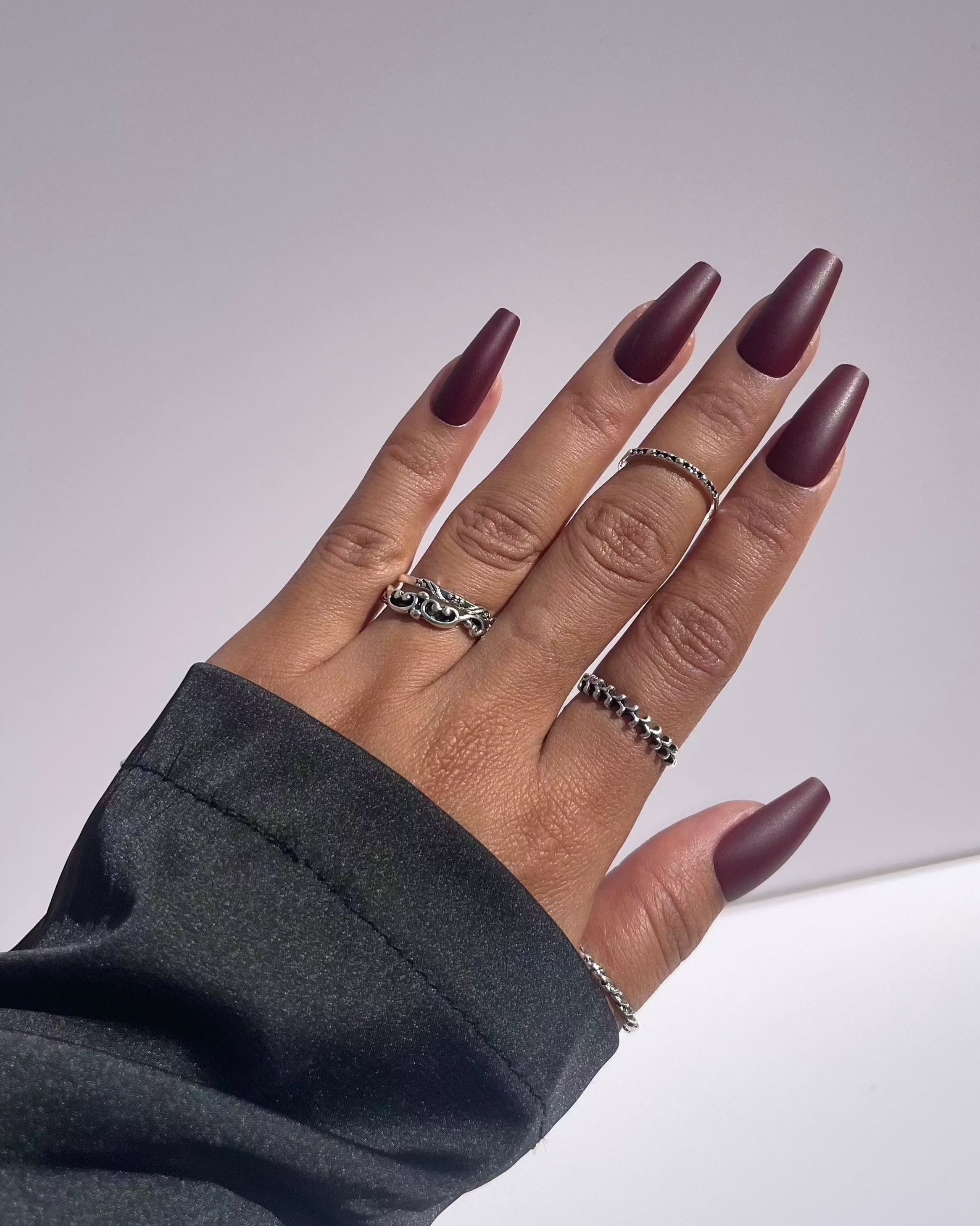 Hand showing burgundy coffin-shaped press-on nails