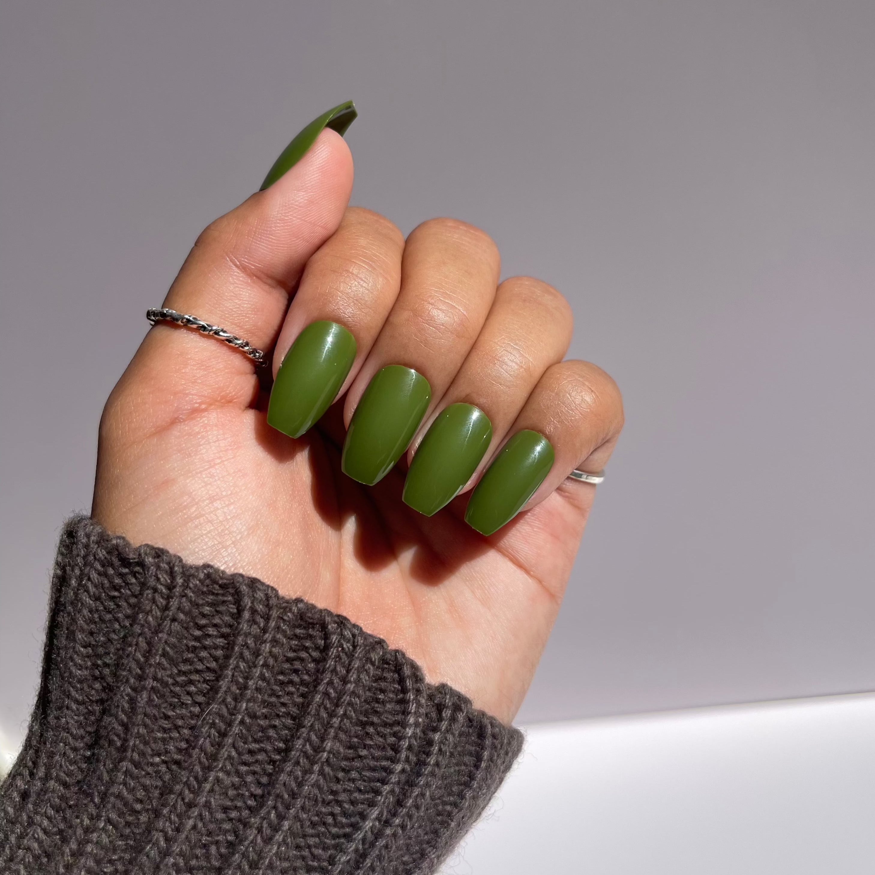 Close-up of olive green press-on nails on hand.