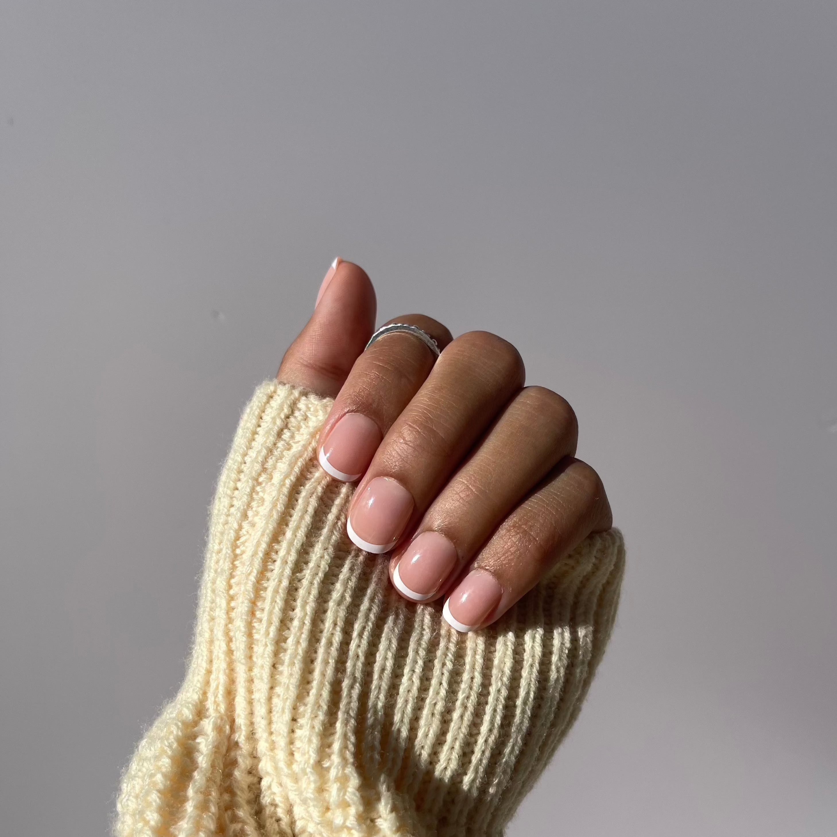 Hand with French manicure press-on nails and sweater