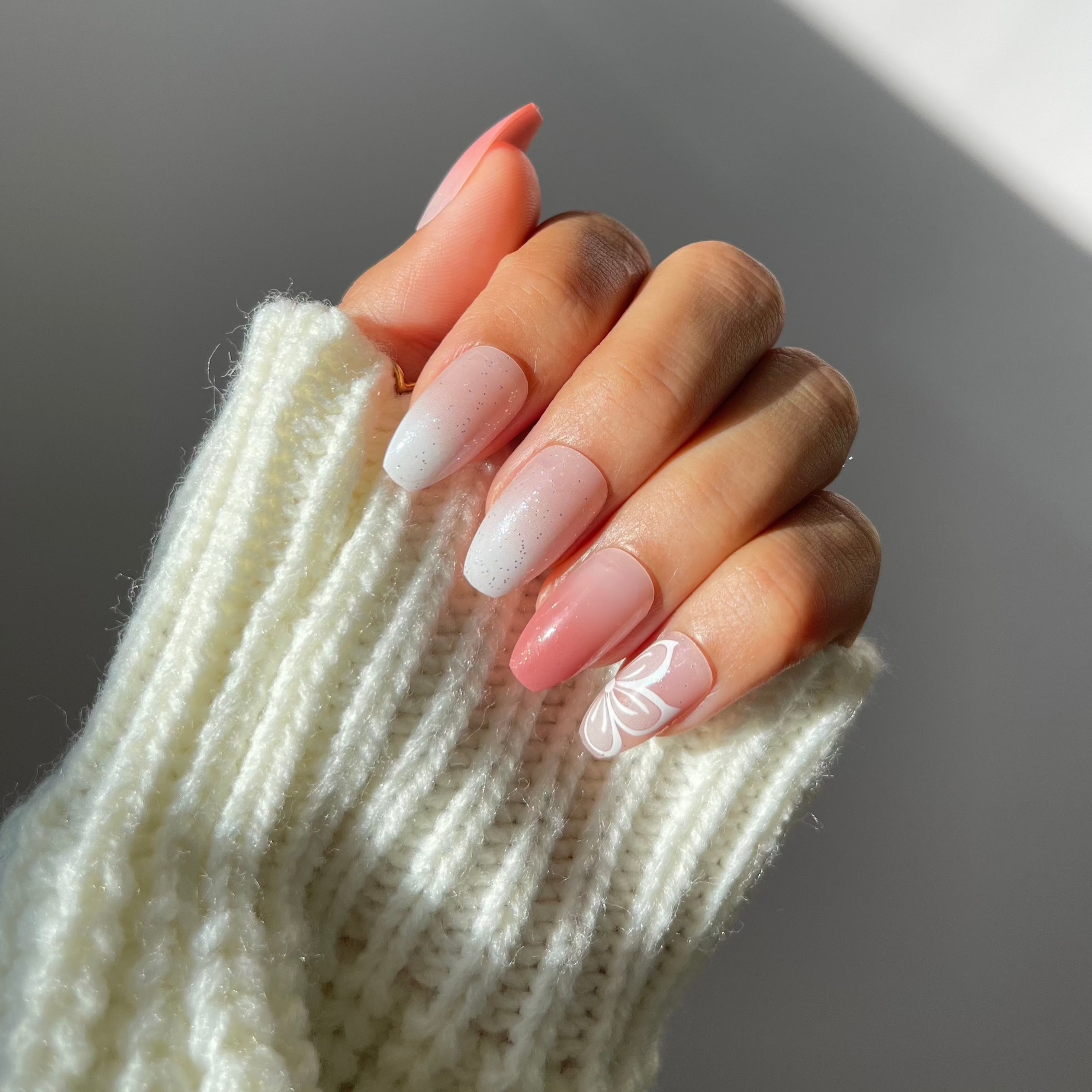 Hand with Iris press-on nails, rosy gradient and floral design.