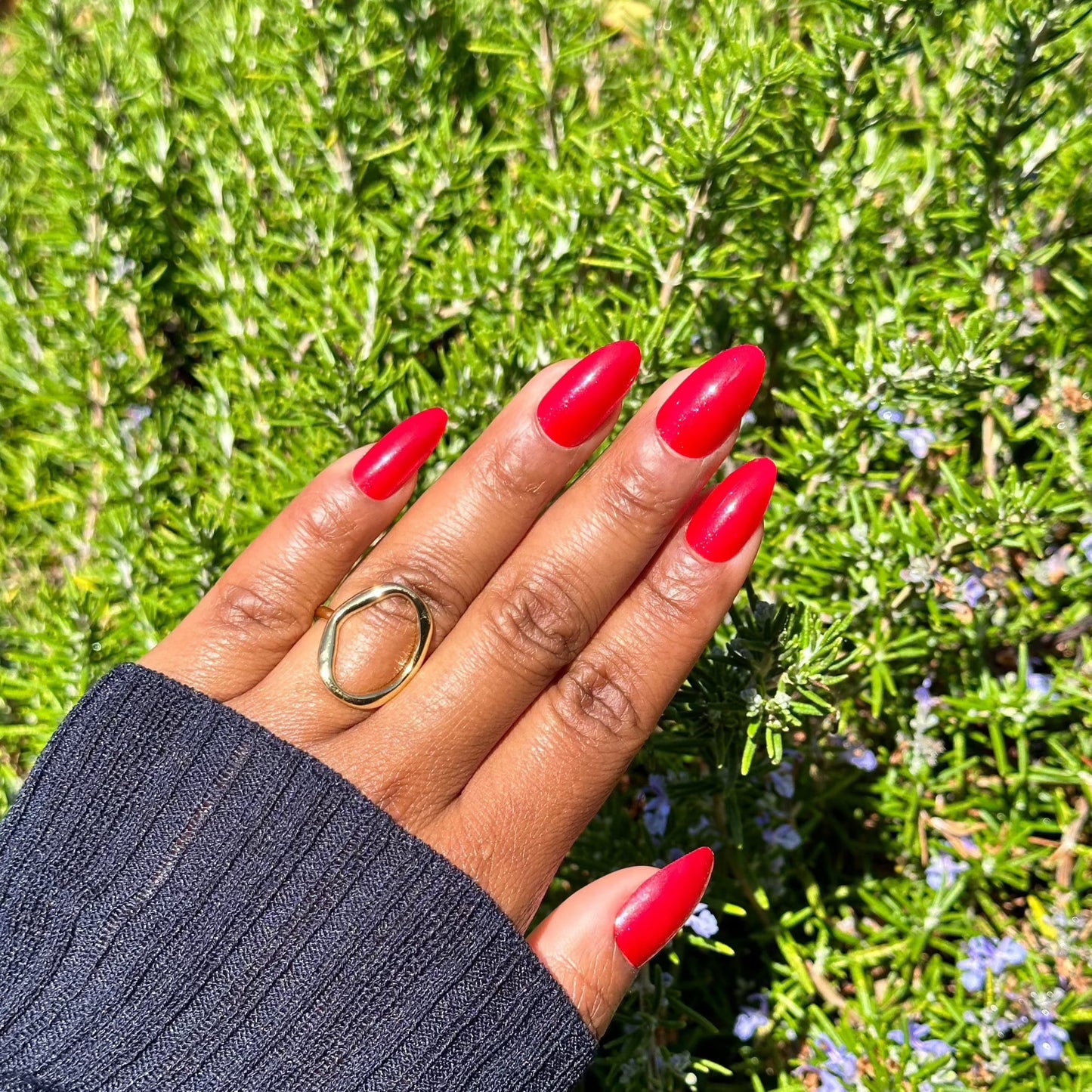 Hand with red press-on nails in sunlight