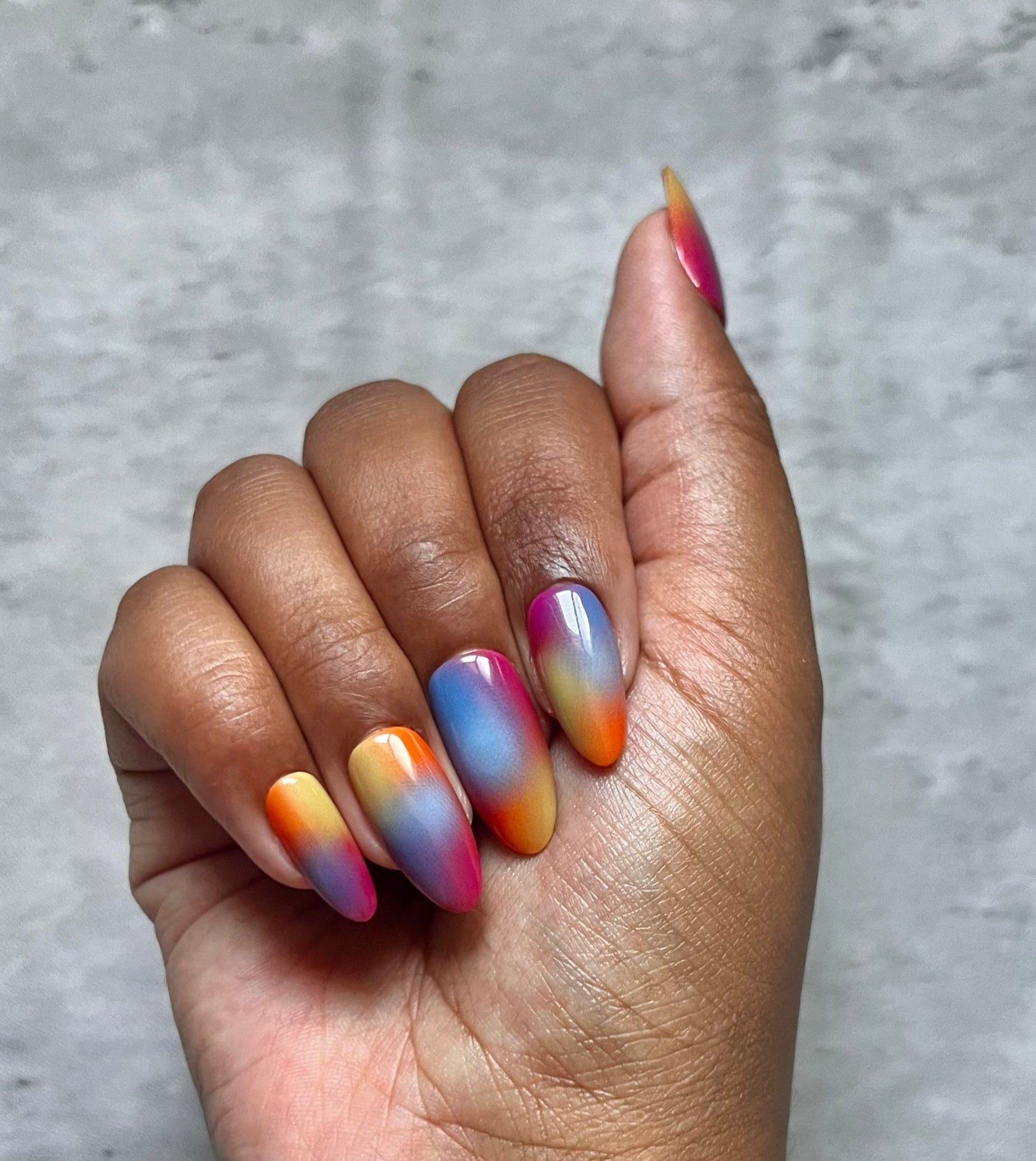Hand with multicolored Press-on nails on a gray background