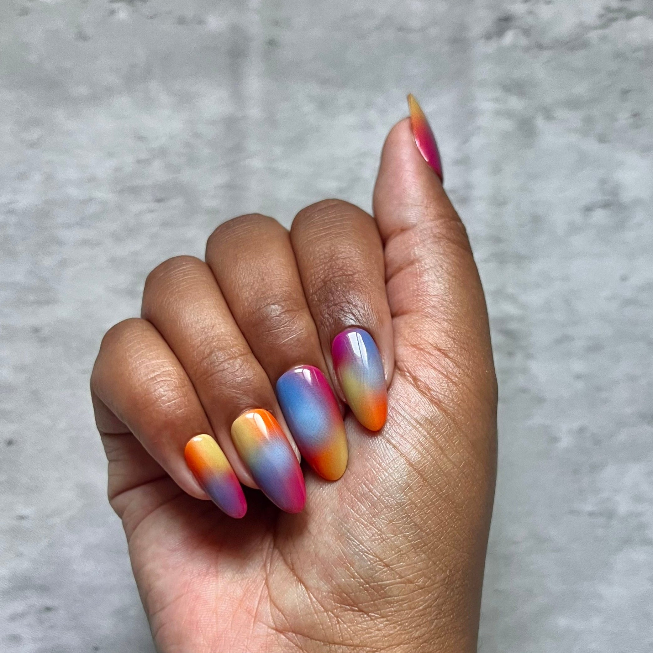 Hand with multicolored Press-on nails on a gray background