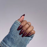 Hand with medium length burgundy press-on nails