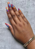 Hand with multicolored press-on nails on a gray background