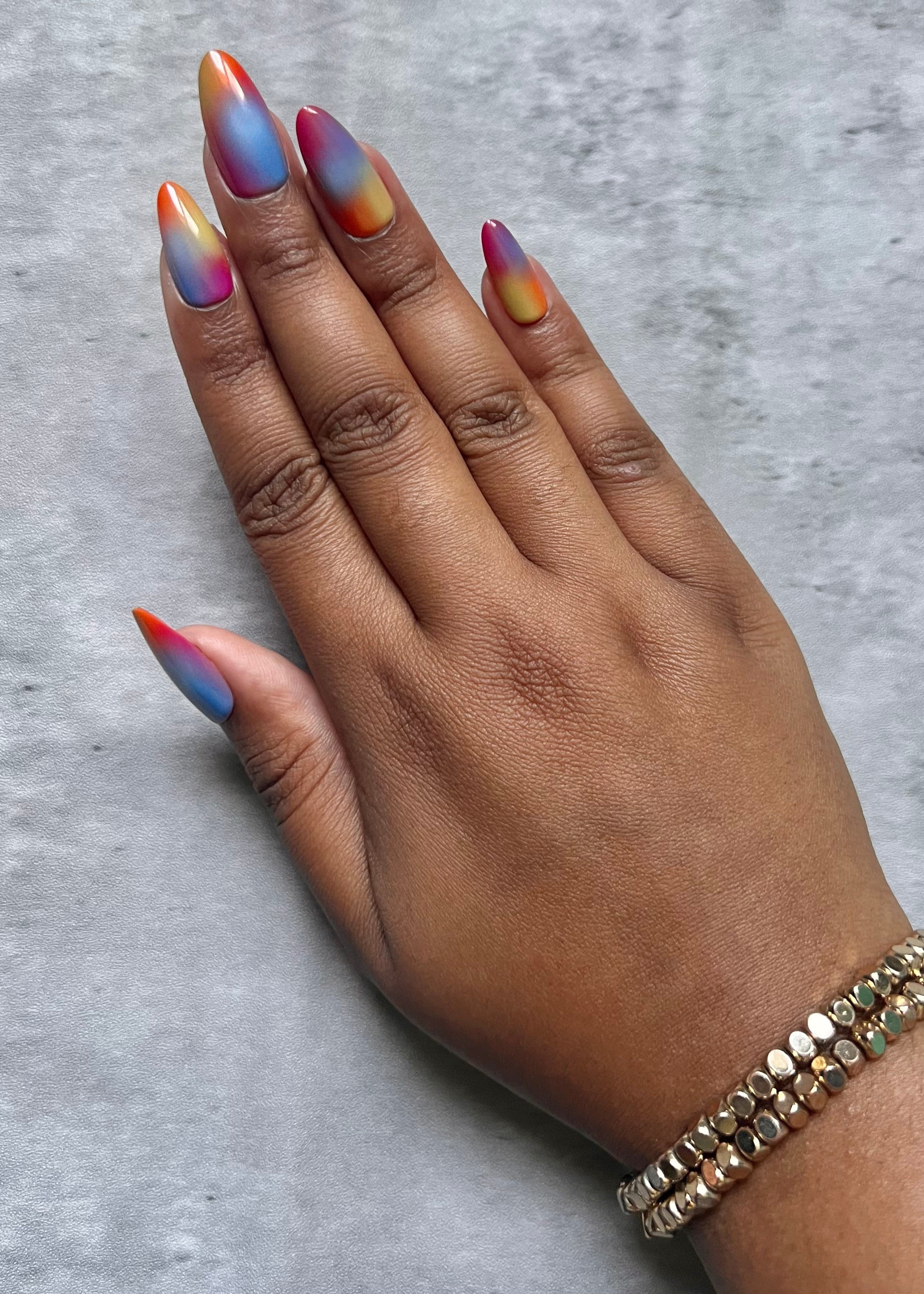 Hand with multicolored press-on nails on a gray background
