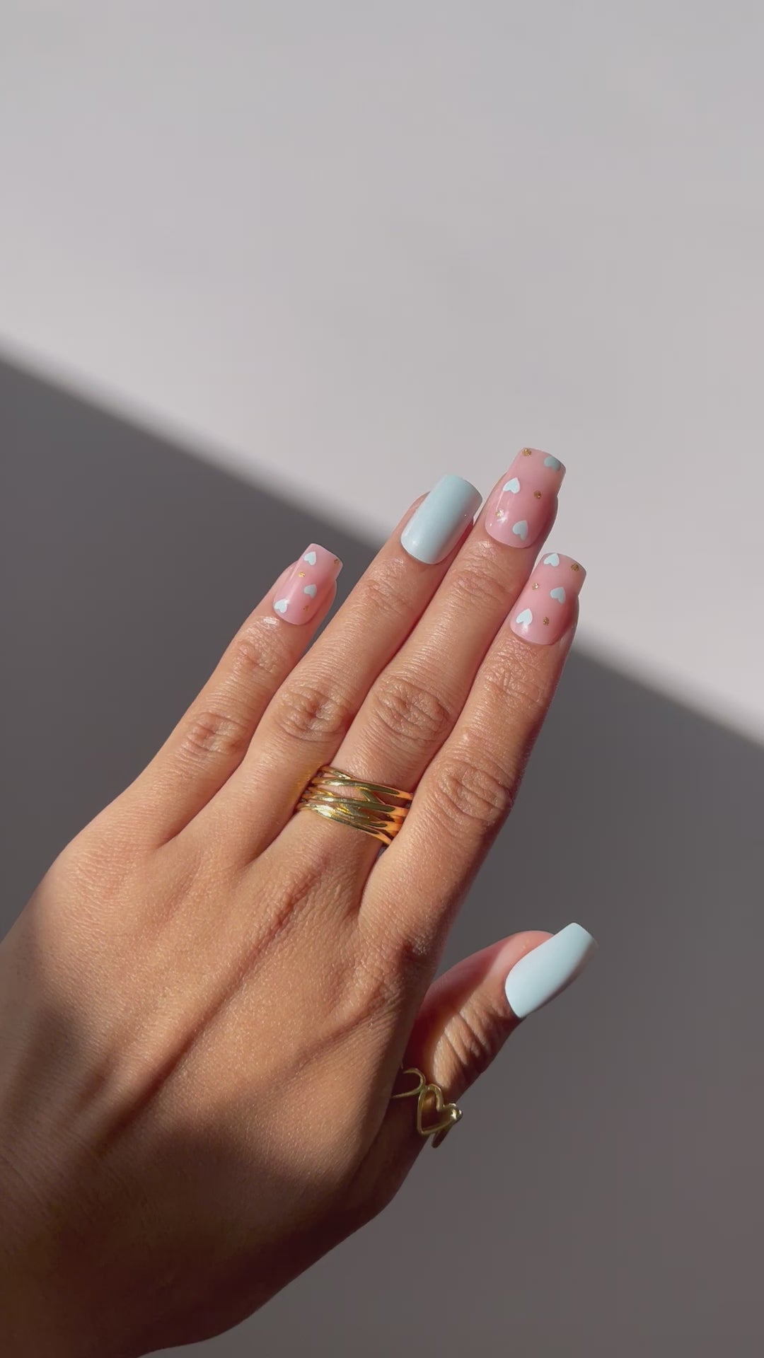 Hand wearing Mila press-on nails in stylish baby blue and pink.