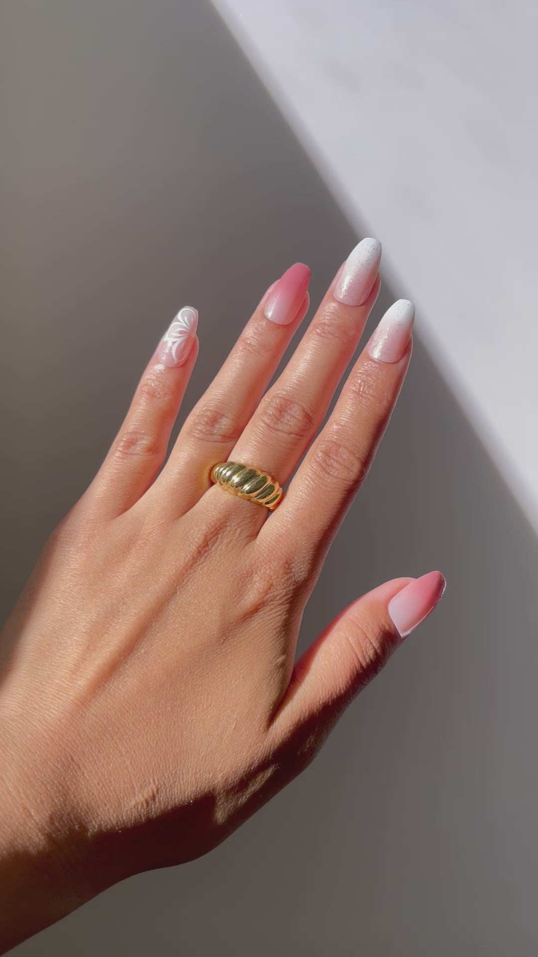 Hand displaying Iris press-on nails with rosy gradient and floral.