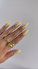 Close-up of yellow almond press-on nails with swirls